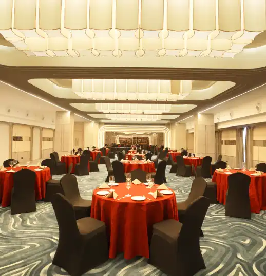 Grand Chamber Hall – Sophisticated Venue for Banquets and Events Elegant banquet hall setup with round tables and red covers under grand ceiling lights