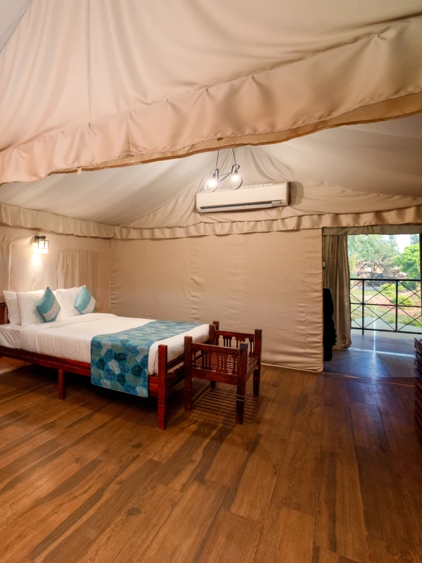 Forest Tent Glamping – Book Eco Stay in Panchgani Forest tent glamping interior with king bed, wooden floor, and garden view at Orchid Hotel Panchgani