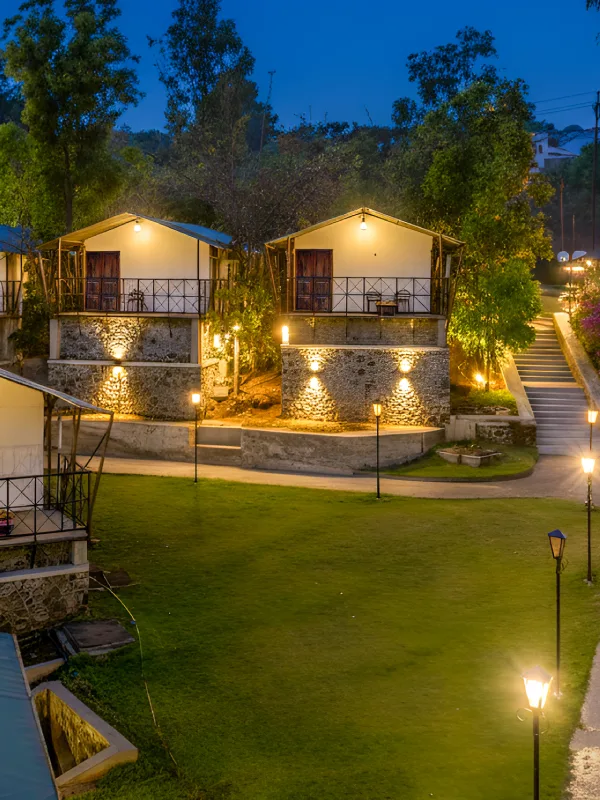 Glamping Tents at Night – Book Unique Stay at Orchid Panchgani Glamping tents with stone base and warm lighting on garden lawn at night, Orchid Hotel Panchgani