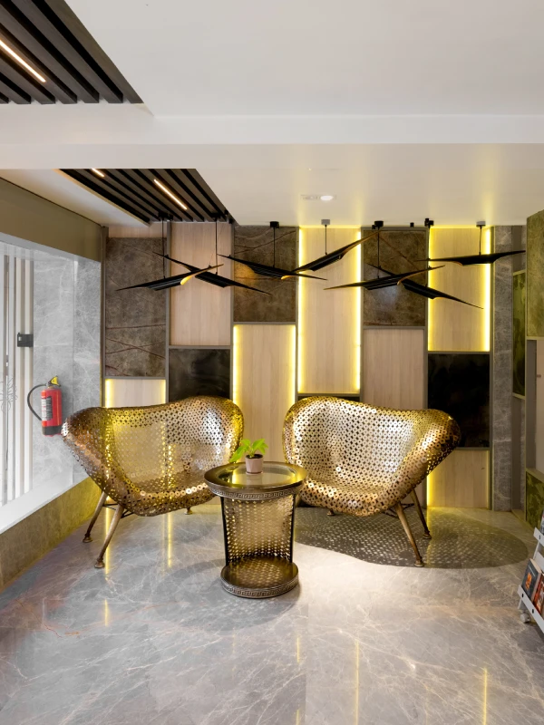 Designer Lobby & Reception – Orchid Hotel Panchgani Hotel lobby with designer gold perforated chairs, ambient lighting, and magazine rack at Orchid Panchgani