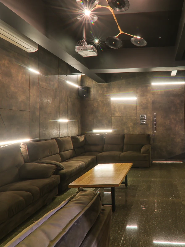 Private Cinema Room – Book Entertainment Stay in Panchgani Private cinema screening room with projector, plush sofas, and mood lighting at Orchid Hotel Panchgani