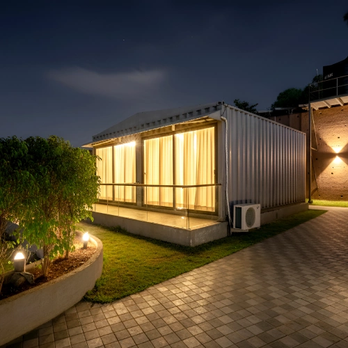 Container Cabin – Unique Stay Orchid Panchgani Container cabin room glowing at night on lawn at Orchid Hotel Panchgani