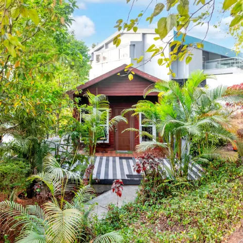 Garden Cottage – Orchid Panchgani Nature Resort Cottage entrance with tropical garden and palm trees at Orchid Hotel Panchgani