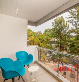 Dew Drop Mist Balcony Room Private Outdoor Seating - Hotel Panchgani Dew Drop Mist Balcony Room private balcony with blue chairs and lush nature view at hotel in Panchgani