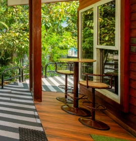 Wooden Cottage Suite Private Balcony - Orchid Hotel Panchgani Private wooden balcony with bar stools and lush green garden view at Wooden Cottage Suite Orchid Hotel Panchgani