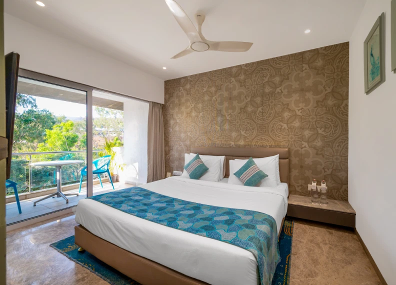 Strawberry Club Room 350 Sqft King Bed with Balcony - Orchid Hotel Panchgani Strawberry Club Room 350 sqft with king bed, teal decor, ornate textured wall, ceiling fan and private balcony nature view at Orchid Hotel Panchgani