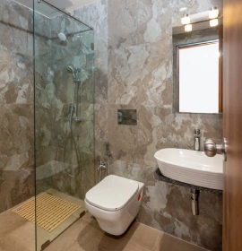 Wooden Tree House Marble Bathroom with Glass Shower - Panchgani Wooden Tree House bathroom with marble tiles, glass shower enclosure, toilet and wall-mounted basin in Panchgani