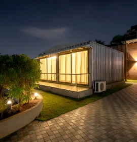Wooden Tree House Night Exterior with Garden - Panchgani Wooden Tree House illuminated exterior with glass windows, AC unit and garden at night in Panchgani